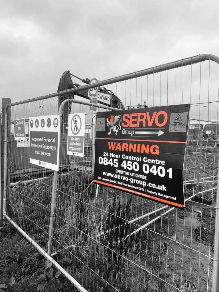 A servo sign on a metal fence on a construction site.